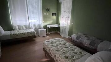 Une chambre avec deux lits, une petite table et une fenêtre avec des rideaux.