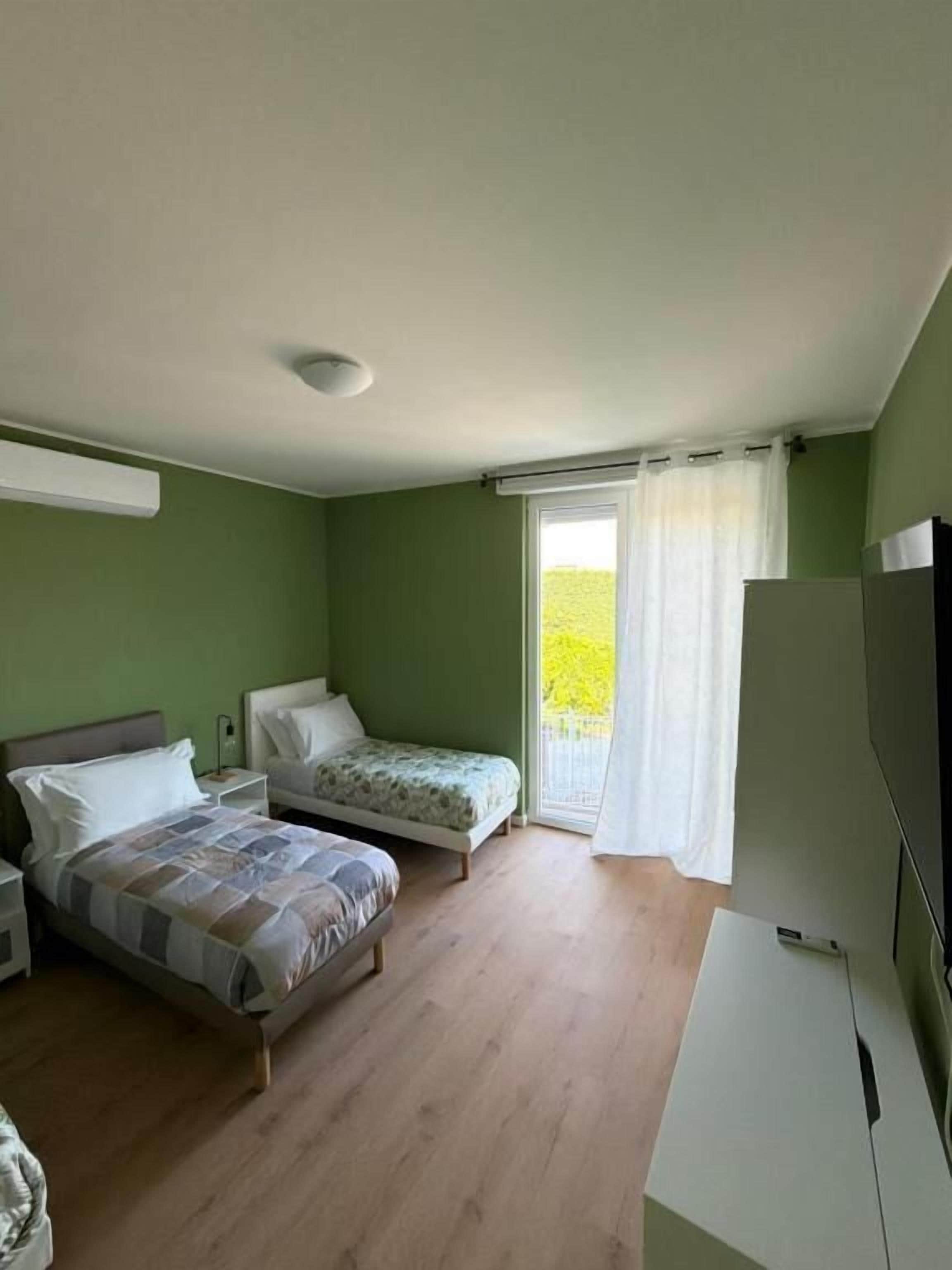 Una camera da letto con due letti, una scrivania e una finestra con tende.