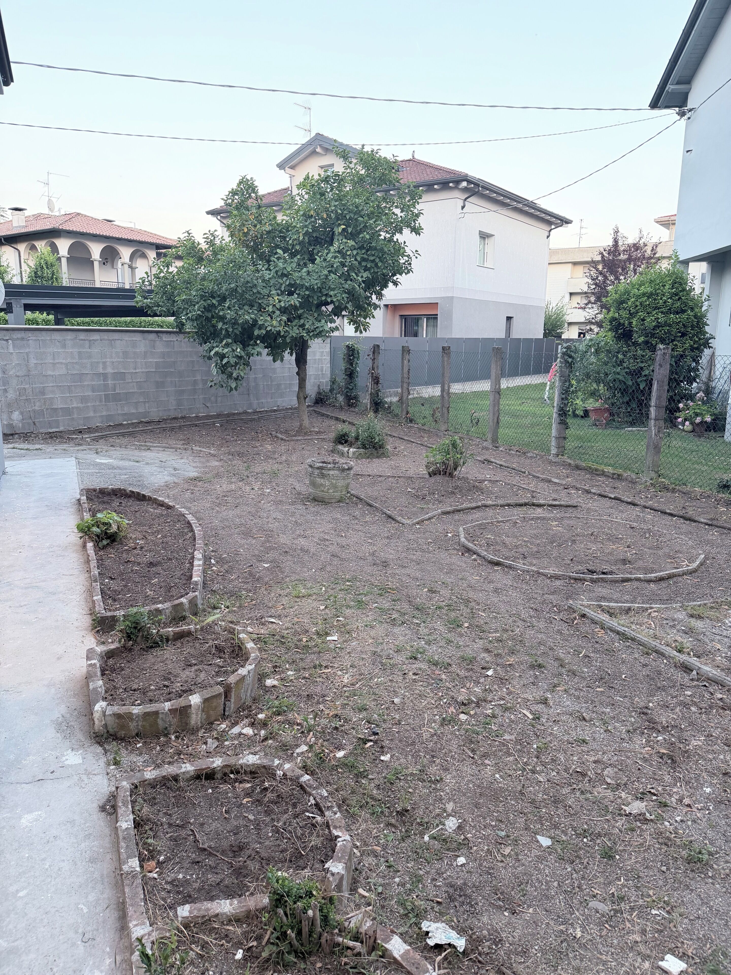 Un jardin avec des plates-bandes surélevées, un arbre et une clôture.