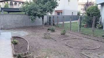 Un jardin avec des plates-bandes surélevées, un arbre et une clôture.