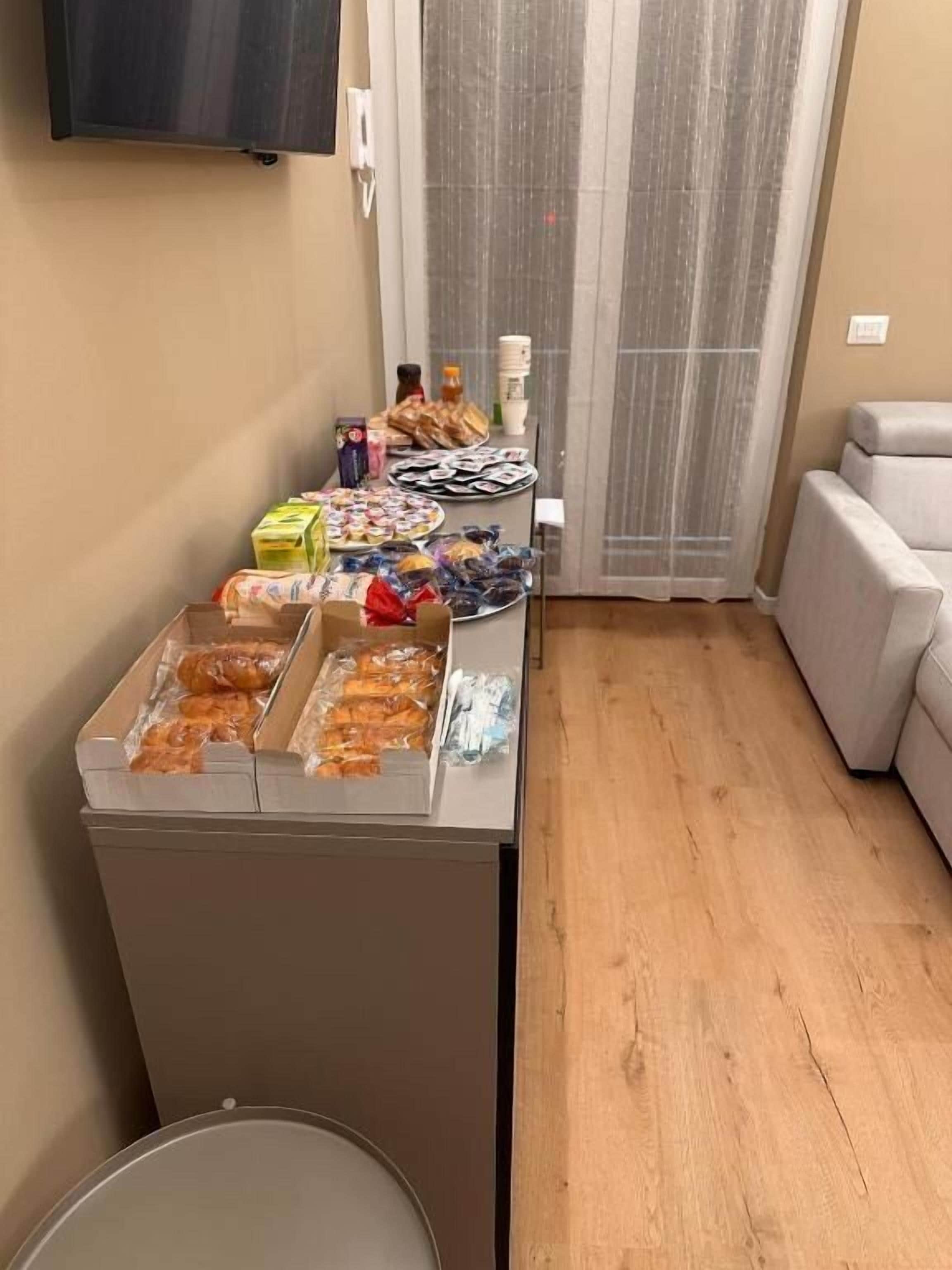 Une chambre dotée d’un coin cuisine comprenant un réfrigérateur, une poubelle et une petite table avec des collations et des boissons.
