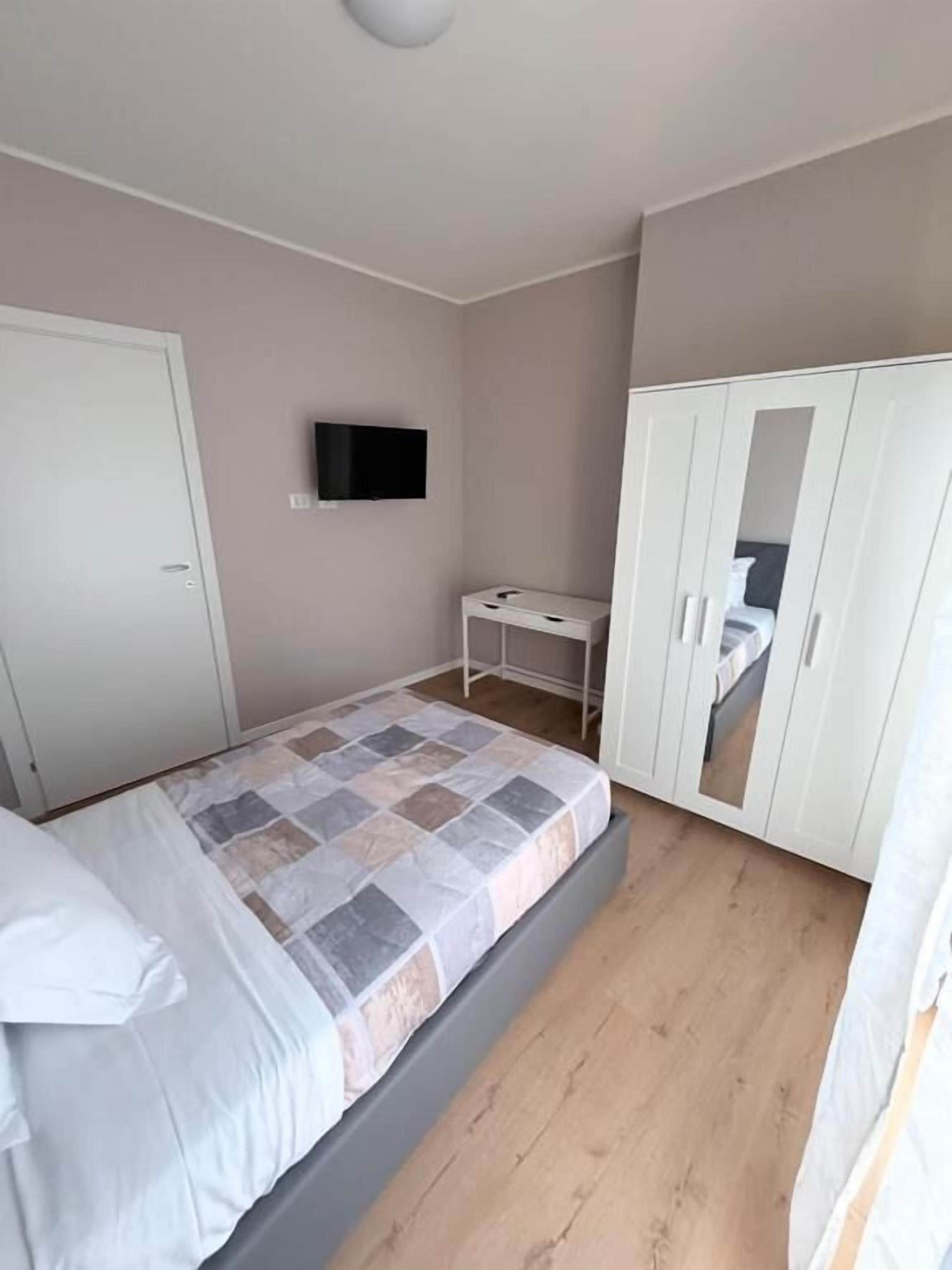 Une chambre à coucher avec un lit, une armoire, une télévision et un bureau.