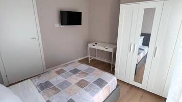 Une chambre à coucher avec un lit, une armoire, une télévision et un bureau.