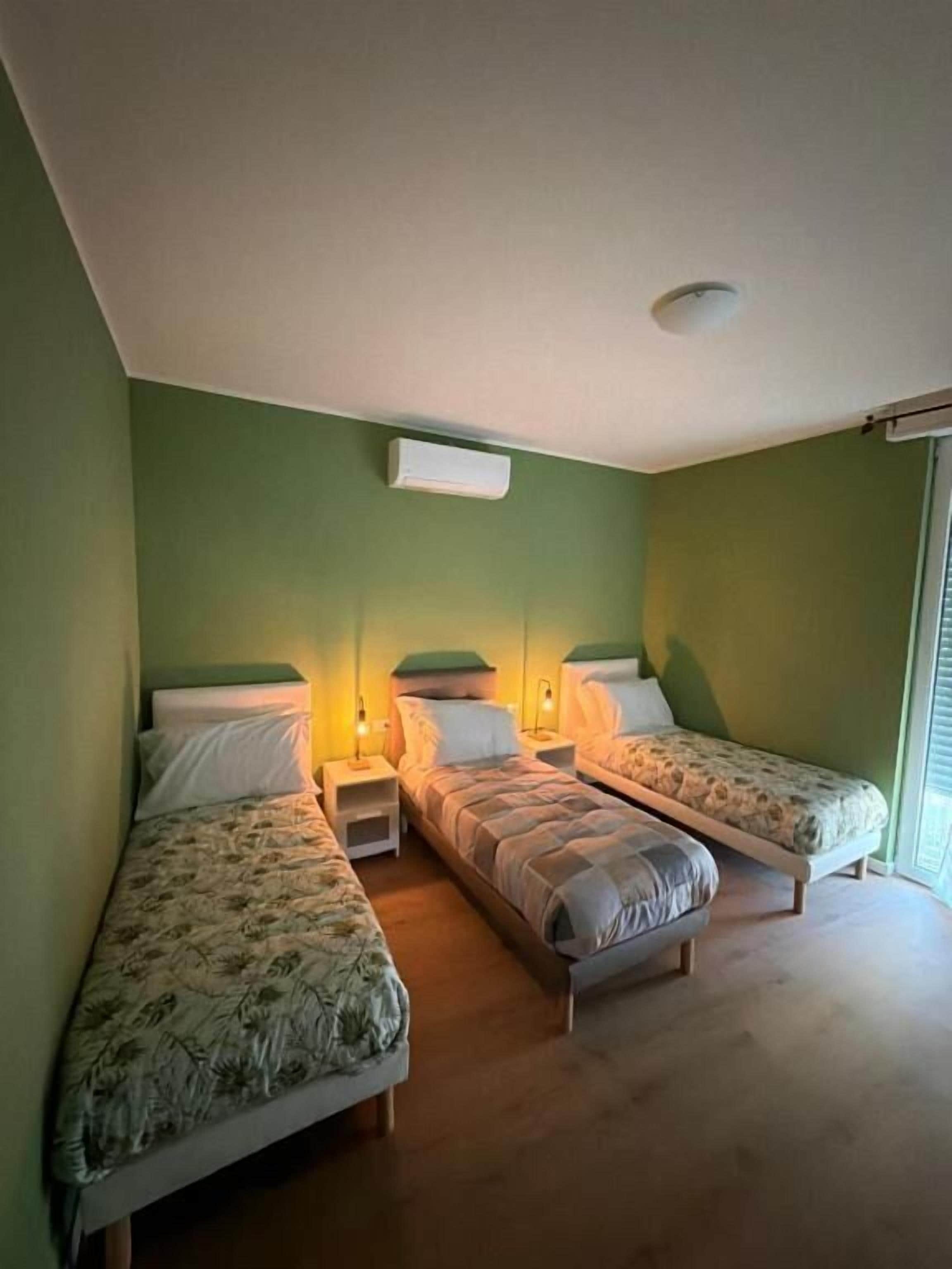 Une chambre avec deux lits simples, une table de chevet et un radiateur fixé au mur.