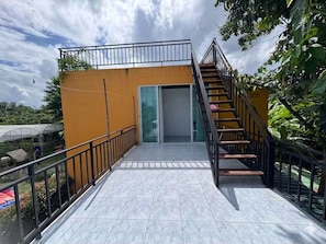A building with a staircase leading to a door, surrounded by a metal railing and a tiled floor.
