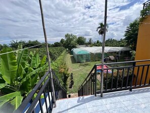 A balcony with a view of a garden and greenhouses.