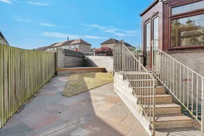 A narrow pathway leading to a wooden staircase with a metal railing. - Spacious 3BR Home, Sleeps 6, Free Parking, Garden (Oakley)