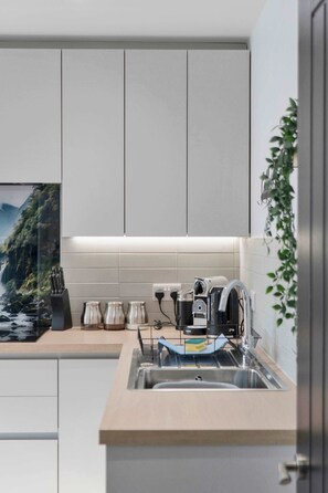 A modern kitchen with a sink, countertop, and a view of a mountainous landscape. - 3 Bed - Nr Edinburgh - Free Parking -Garden -Wi-Fi (Oakley)