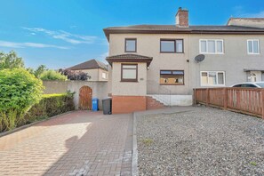 A residential property with a paved driveway, a wooden fence, and a gravel area. - Spacious 3BR Home, Sleeps 6, Free Parking, Garden (Oakley)