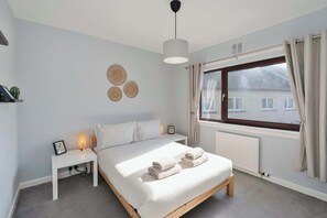 A bedroom with a bed, bedside table, lamp, and a window with curtains. - 3 Bed - Nr Edinburgh - Free Parking -Garden -Wi-Fi (Oakley)