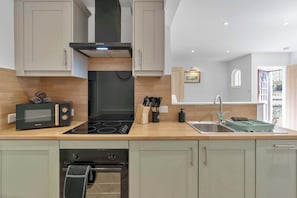 A modern kitchen with a built-in oven, microwave, and stove. - 1BR Selkirk Town Centre Flat, Parking, Sleeps 4 (Scottish Borders)