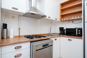 Une cuisine moderne avec des meubles blancs, une cuisinière en acier inoxydable, un lave-vaisselle et un four à micro-ondes.