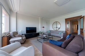 A modern living room with a flat-screen TV, sofas, a coffee table, and a large mirror. - Bosphorus View with Balcony - 3 Bedrooms 2 Bathrooms (İstanbul)
