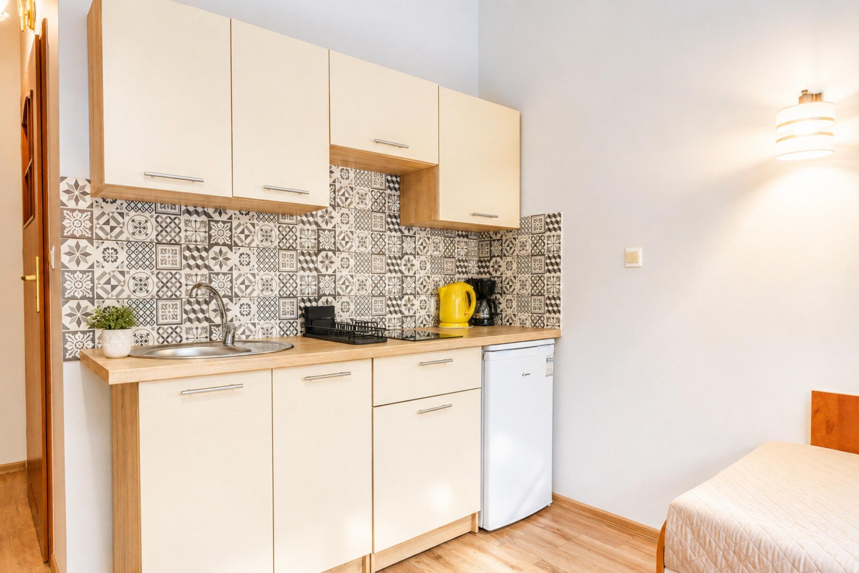 A compact kitchenette with a sink, a coffee maker, and a small refrigerator.