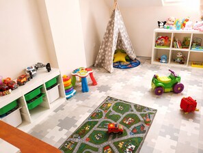 Ein Kinderzimmer mit Puzzleteppich, Spielzeug und Stauraumelementen.