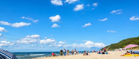 Una playa con gente, sombrillas y cielo despejado.