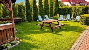 A well-maintained backyard with a wooden picnic table and white lounge chairs. - Studio for 3 People, Rewal (Rewal)