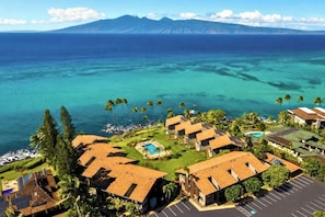 A resort with multiple buildings, a swimming pool, and a view of the ocean.