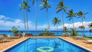 Piscina com vista tropical, rodeada por palmeiras e espreguiçadeiras.