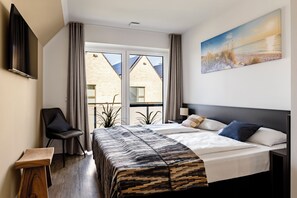 A hotel room with a bed, a chair, a desk, and a painting on the wall. - 106-square-meter vacation home with a sauna and fireplace on the dike (Büsum)