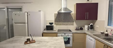 Una cocina moderna con una isla central, electrodomésticos integrados y una campana extractora de acero inoxidable.