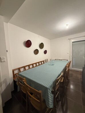 A dining area with a table set for six, wooden chairs, and a blue checkered tablecloth.