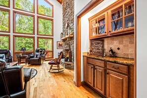 A spacious living area with large windows, a fireplace, and wooden cabinetry. - Sleeps 15!|Indoor Fireplace|HotTub|Pets OK|Game RM (Beech Mountain)