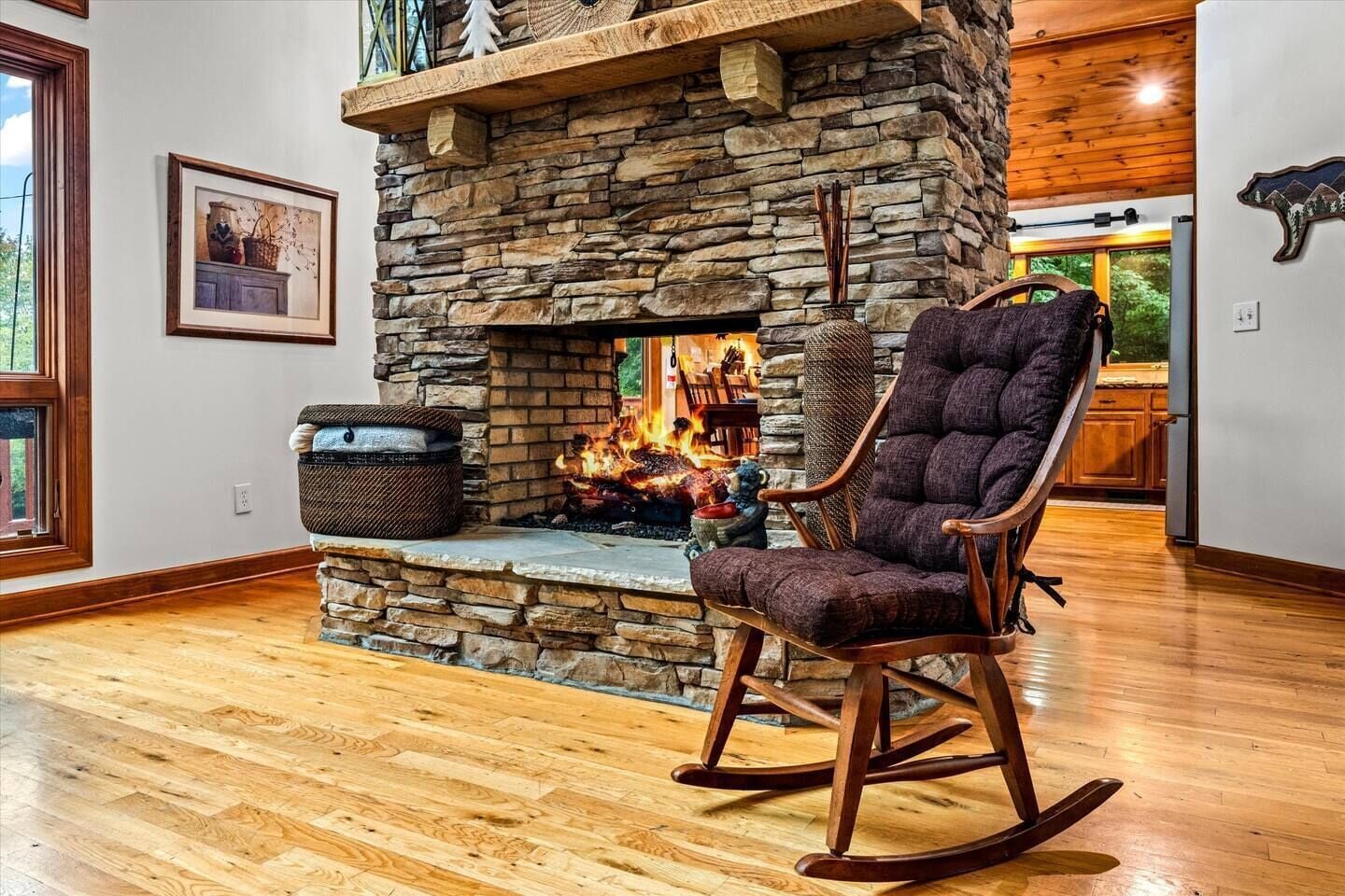 A cozy room with a stone fireplace, a rocking chair, and a wooden floor.
