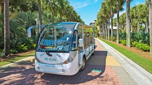 A beach tram with "The Village" branding parked on a paved path surrounded by palm trees and greenery. - 4BR in Seacrest Beach w 4 Bikes & Lagoon Pool Views + Attraction Tickets! (Panama City Beach)
