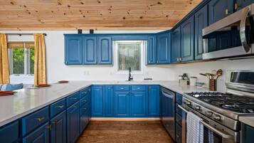 Eine moderne Küche mit blauen Schränken, einer Holzbalkendecke und Edelstahlgeräten.