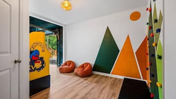 Ein Zimmer mit Holzboden, einer Kletterwand und zwei Sitzsäcken.