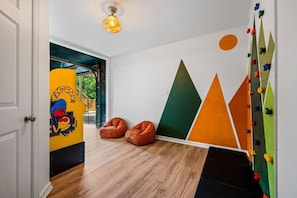 Una habitación con piso de madera, una pared de escalada y dos sillones de pelota.