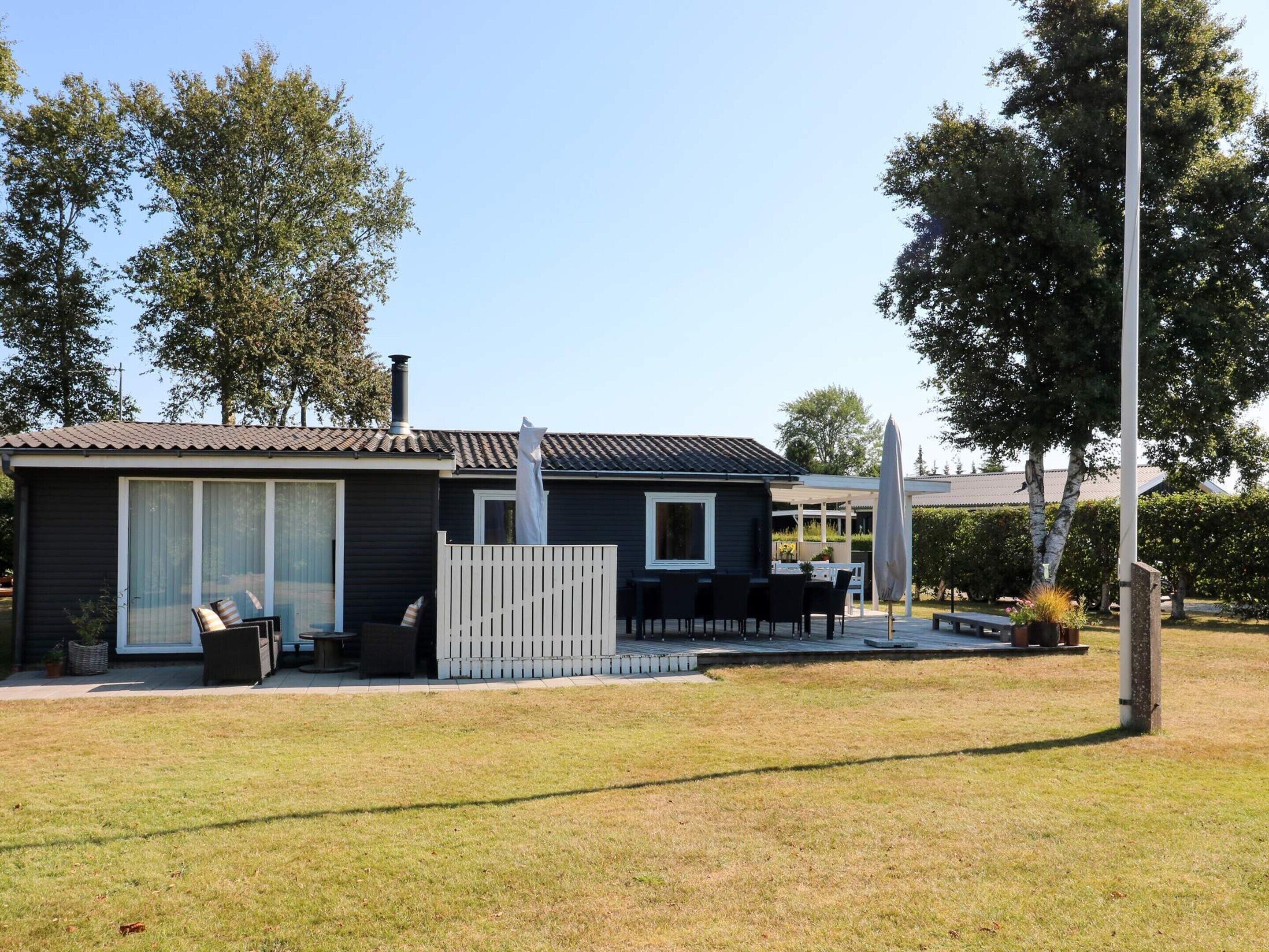 A single-story house with a patio area, a chimney, and a fenced deck.