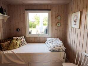 Ein kleines, gemütliches Zimmer mit einem Einzelbett, einem Fenster und einer Wanduhr.