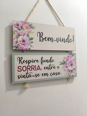 A wall-mounted sign with floral designs and inspirational text. - Cozy loft in Tauá, offering total privacy to guests and easy access. (Rio de Janeiro)