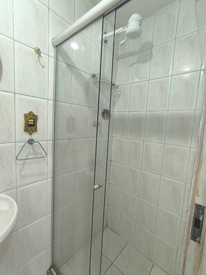 A shower with a glass door, a towel rack, and a wall-mounted light fixture.