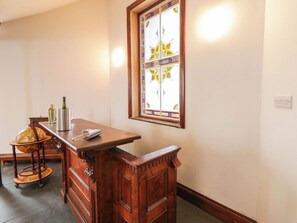 A room with a wooden bar counter, a globe, a bottle, and a decorative window.