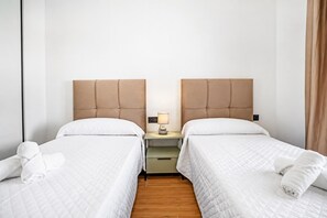 Ein Hotelzimmer mit zwei Betten, einem Nachttisch mit Lampe und Holzboden.