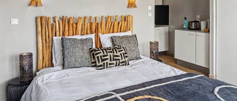 A bedroom with a wooden headboard, a bed with patterned pillows, and two wall-mounted lamps.