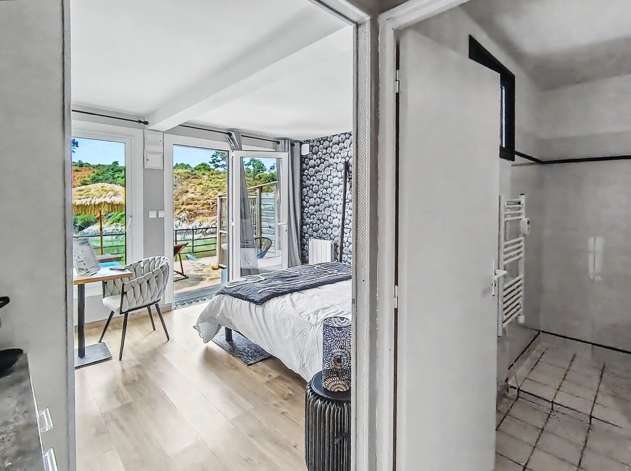 A bedroom with a bed, a chair, and a view of the outdoors.
