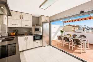 Uma cozinha moderna com eletrodomésticos de aço inoxidável e uma sala de jantar com mesa e cadeiras.