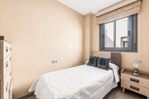 Ein Schlafzimmer mit einem Bett, einem Nachttisch, einer Lampe und einem Fenster mit Blick.