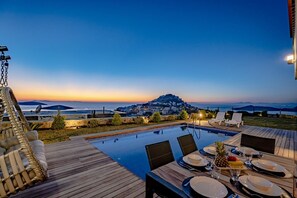 A poolside dining area with a view of the sea and a hill in the background. - Villa Nerea - Three Bedroom Villa, Sleeps 6 (Geriş Mahallesi)