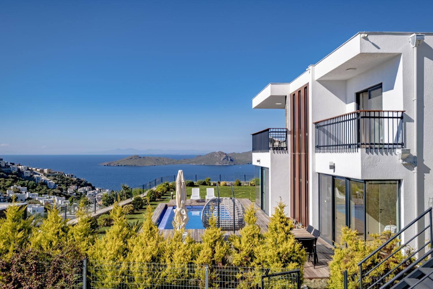 A modern building with a pool, a balcony, and a view of the sea.