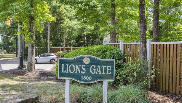 A sign reading 'Lions Gate 1800' with a wooden fence and trees in the background. - Coastal Gem near Wrightsville Beach, Golf & Dining (Wilmington)