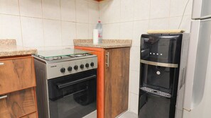 Ett kompakt kök med en gasspis, ugn och ett kylskåp.