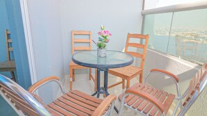 Ein Balkon mit einem runden Tisch, vier Holzstühlen und einem Blumentopf mit rosa Blüten.
