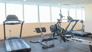 Une salle de sport équipée de tapis de course, d’un appareil elliptique et de machines de musculation.