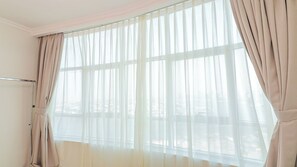 Une pièce dotée d’une grande fenêtre, d’un radiateur en métal et d’une tringle à rideaux.