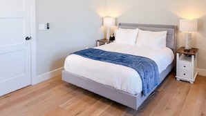 A bedroom with a bed, bedside tables, and lamps. - Lakeside 2-bedroom condo in awesome Laconia (Laconia)
